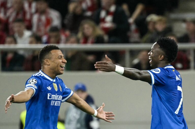 Real Madrid's French forward #10 Kylian Mbappe (L) celebrates with Real Madrid's Brazilian forward #07 Vinicius Junior after scoring Real Madrid's third goal during the UEFA Champions League, league phase - matchday 5, football match between Olympiakos (GRE) and Real Madrid (ESP) at the Georgios Karaiskakis Stadium in Piraeus on November 26, 2025. (Photo by Angelos Tzortzinis / AFP)
